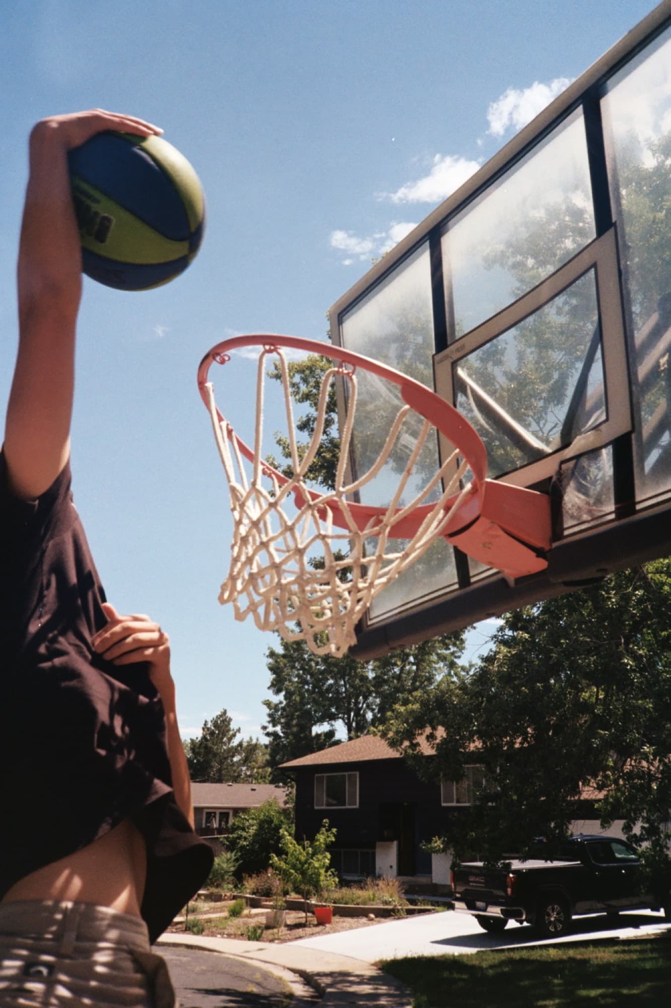 Shooting a basketball at a driveway hoop against a blue summer sky